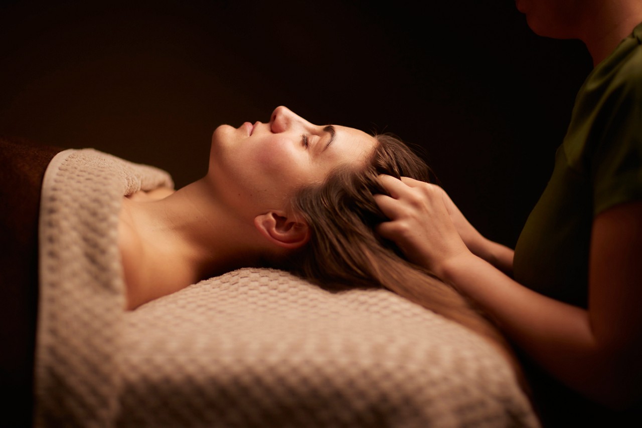 Spa therapist giving a woman a relaxing scalp massage.